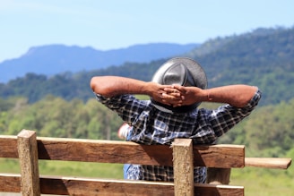 a man resting his head on a wooden fence