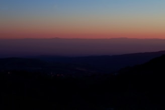 An atmospheric horizon with layered hills fading into a serene, pastel sky at dusk.