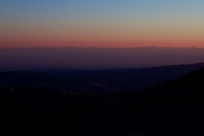 An atmospheric horizon with layered hills fading into a serene, pastel sky at dusk.