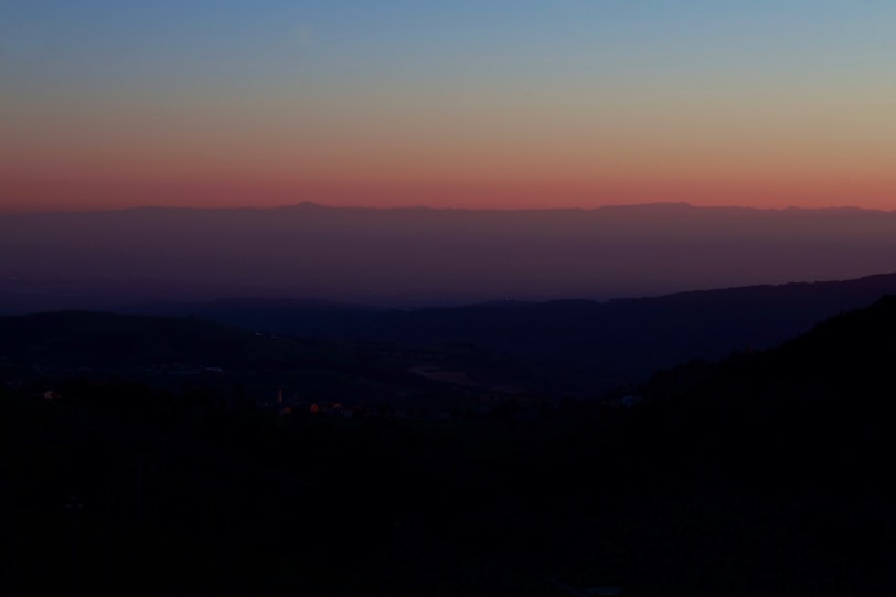 An atmospheric horizon with layered hills fading into a serene, pastel sky at dusk.