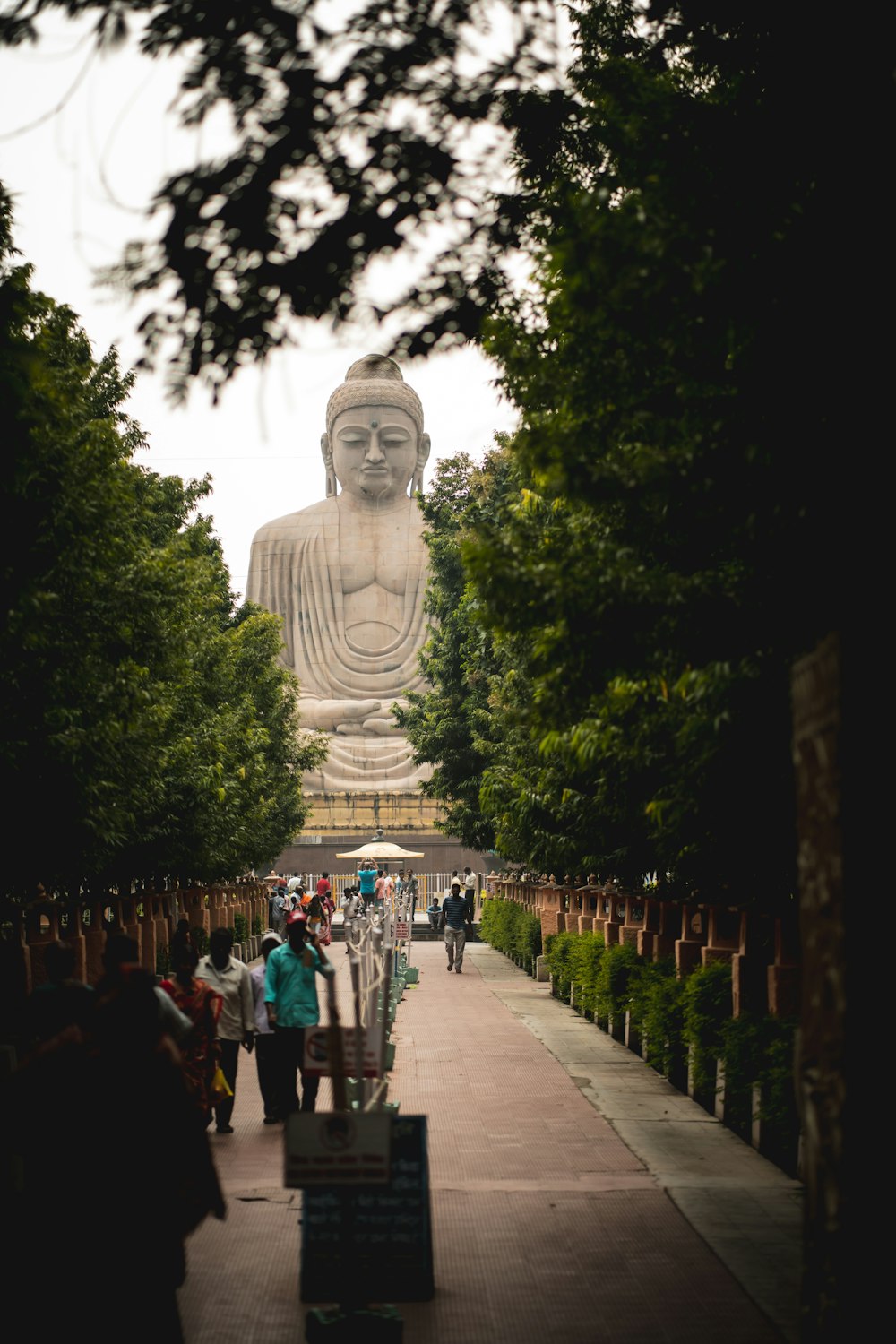 a large statue of a person with a crown on a path with trees