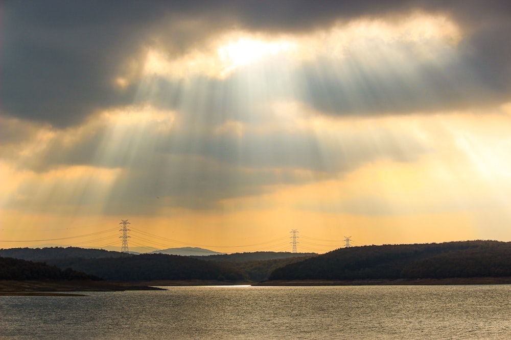 a body of water with hills and power lines in the distance