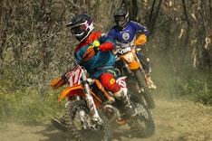two people riding dirt bikes