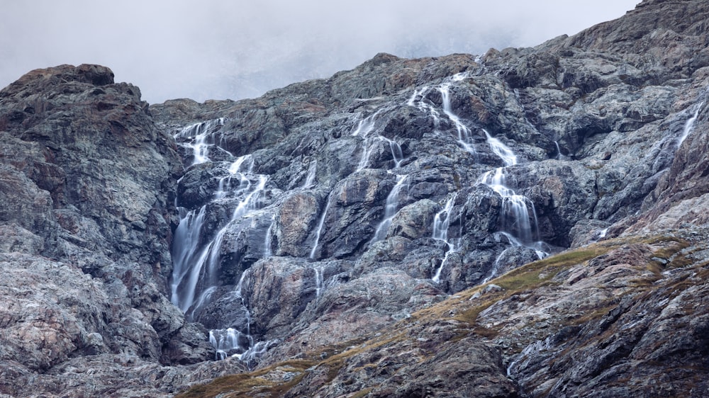 a rocky mountain with a waterfall