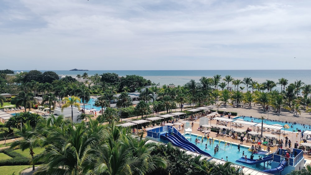 a pool with people in it by a beach with trees and water