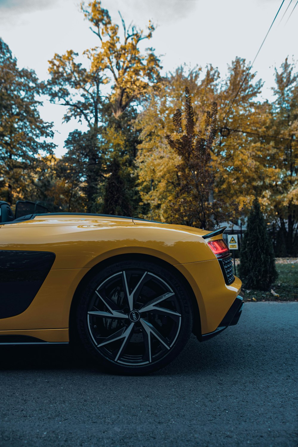 a yellow sports car parked on a road with trees in the background