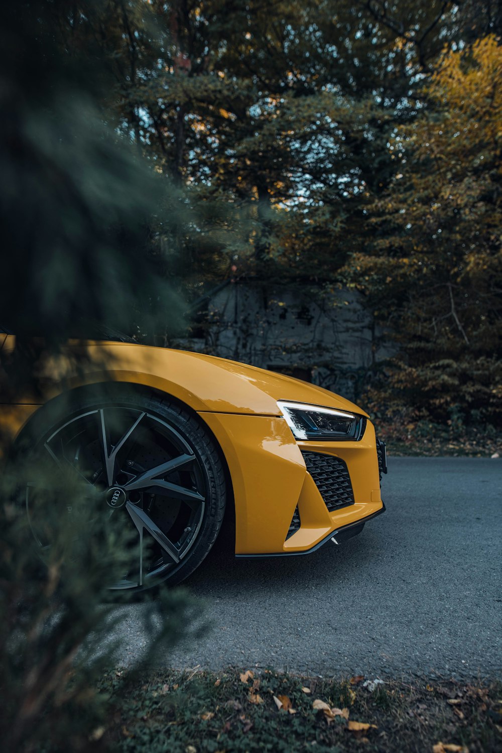 a yellow sports car parked on a road with trees on either side