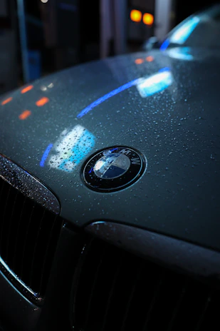 Close-up of a shiny BMW car hood with a reflection of the workshop lights.
