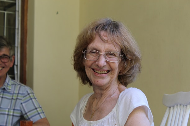 A warm consultation scene between a hearing specialist and a smiling elderly woman in a cozy clinic setting.