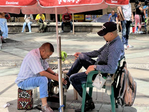 A vibrant electric cart parked on a city street with a young person handing over sneakers for cleaning