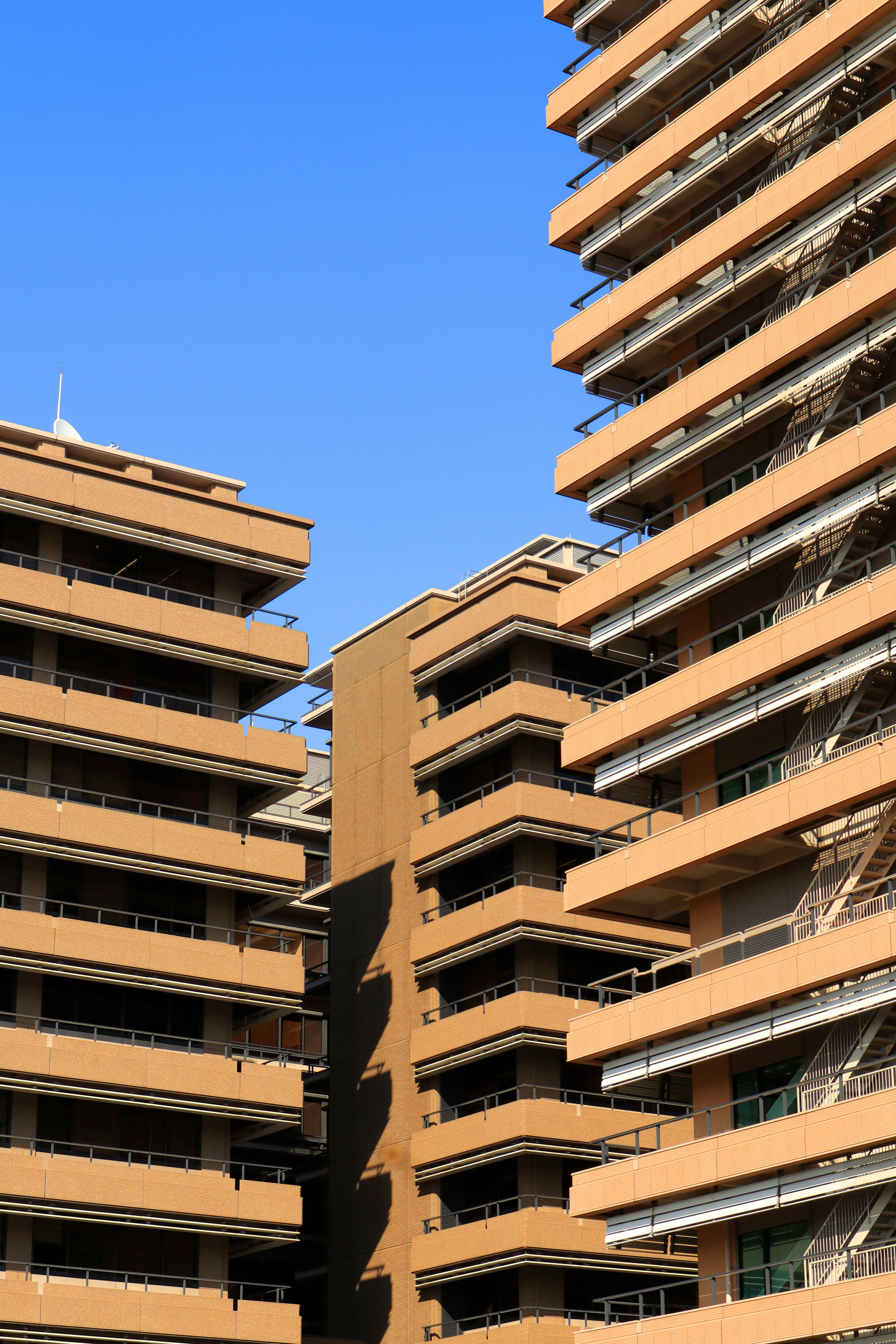 Modern Indian apartment building exterior in afternoon light, deep blue sky, clean architecture