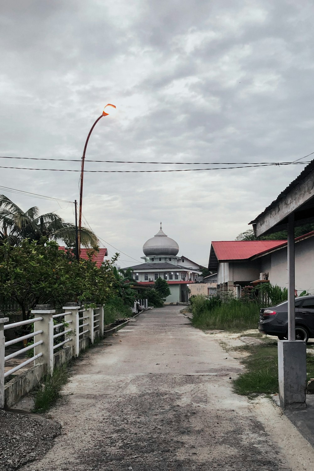 a road with a white fence and a white building with a dome on top