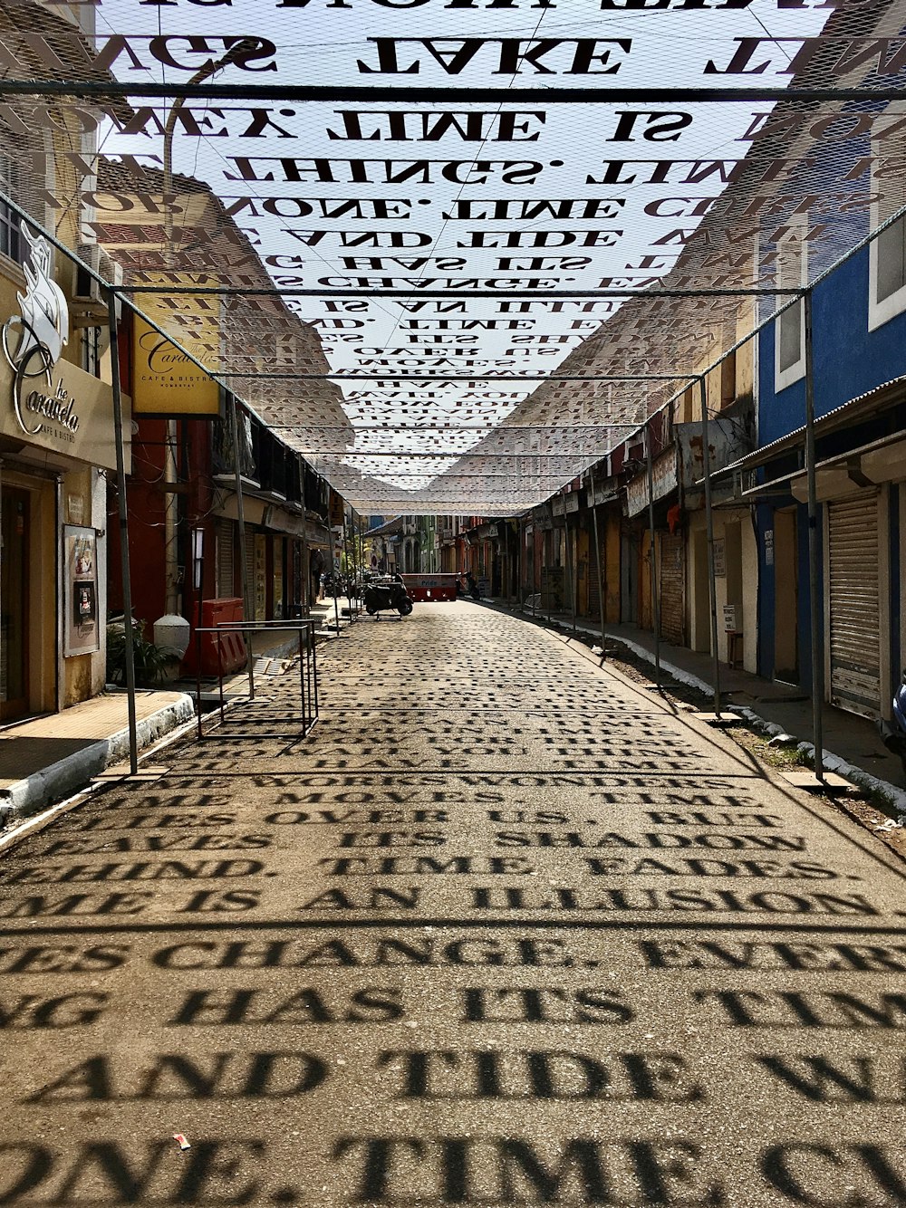 a brick road with a metal frame over it and buildings on the side