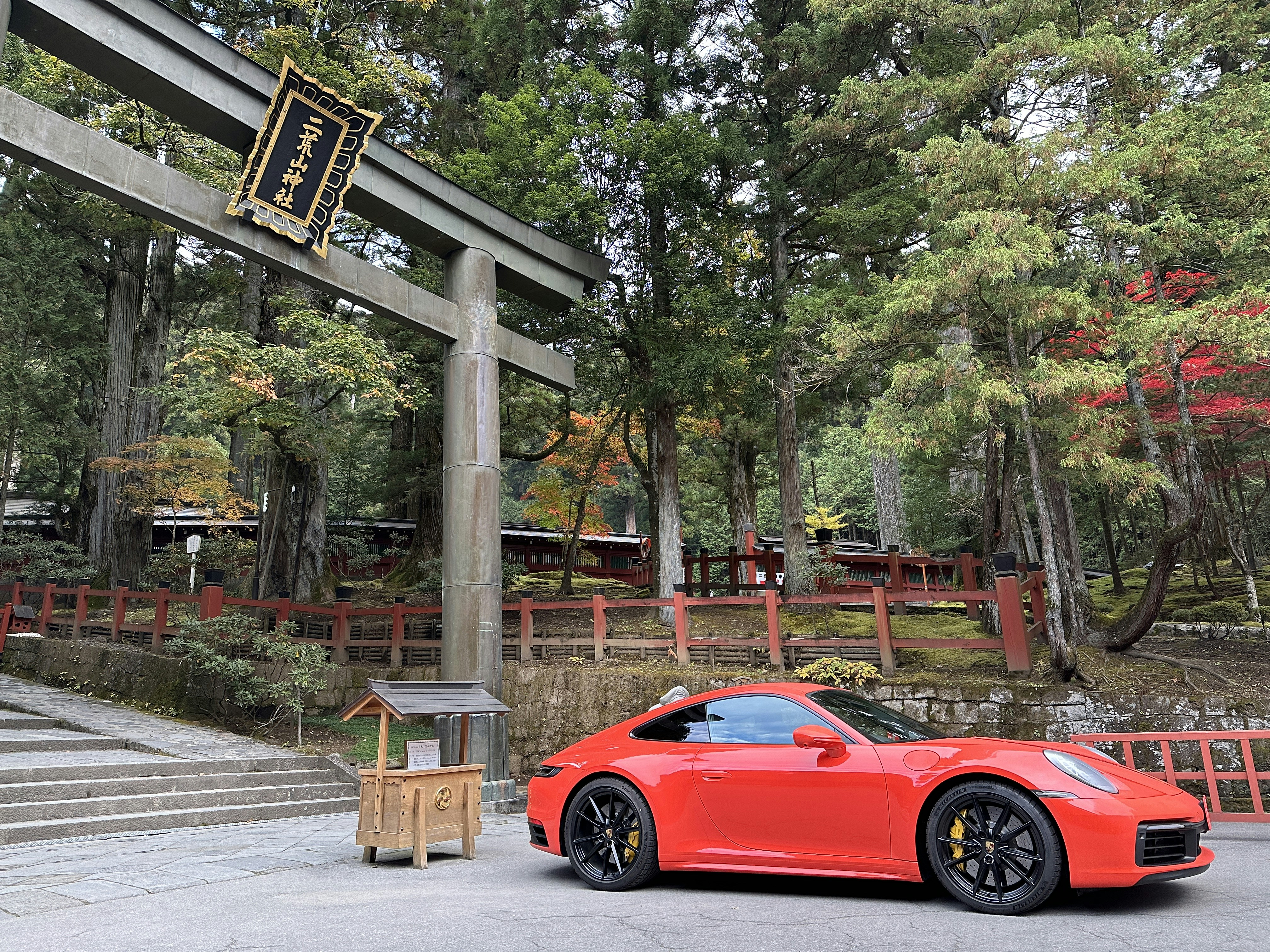 a red sports car parked in front of a wooden structure