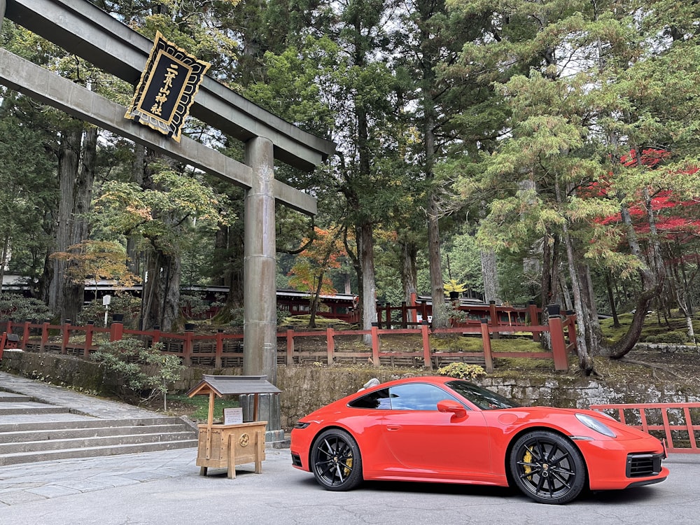 a red sports car parked in front of a wooden structure