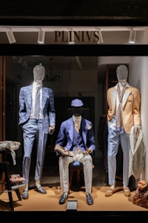 a man sitting on a stool in front of a display of mannequins