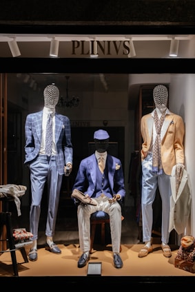 a man sitting on a stool in front of a display of mannequins