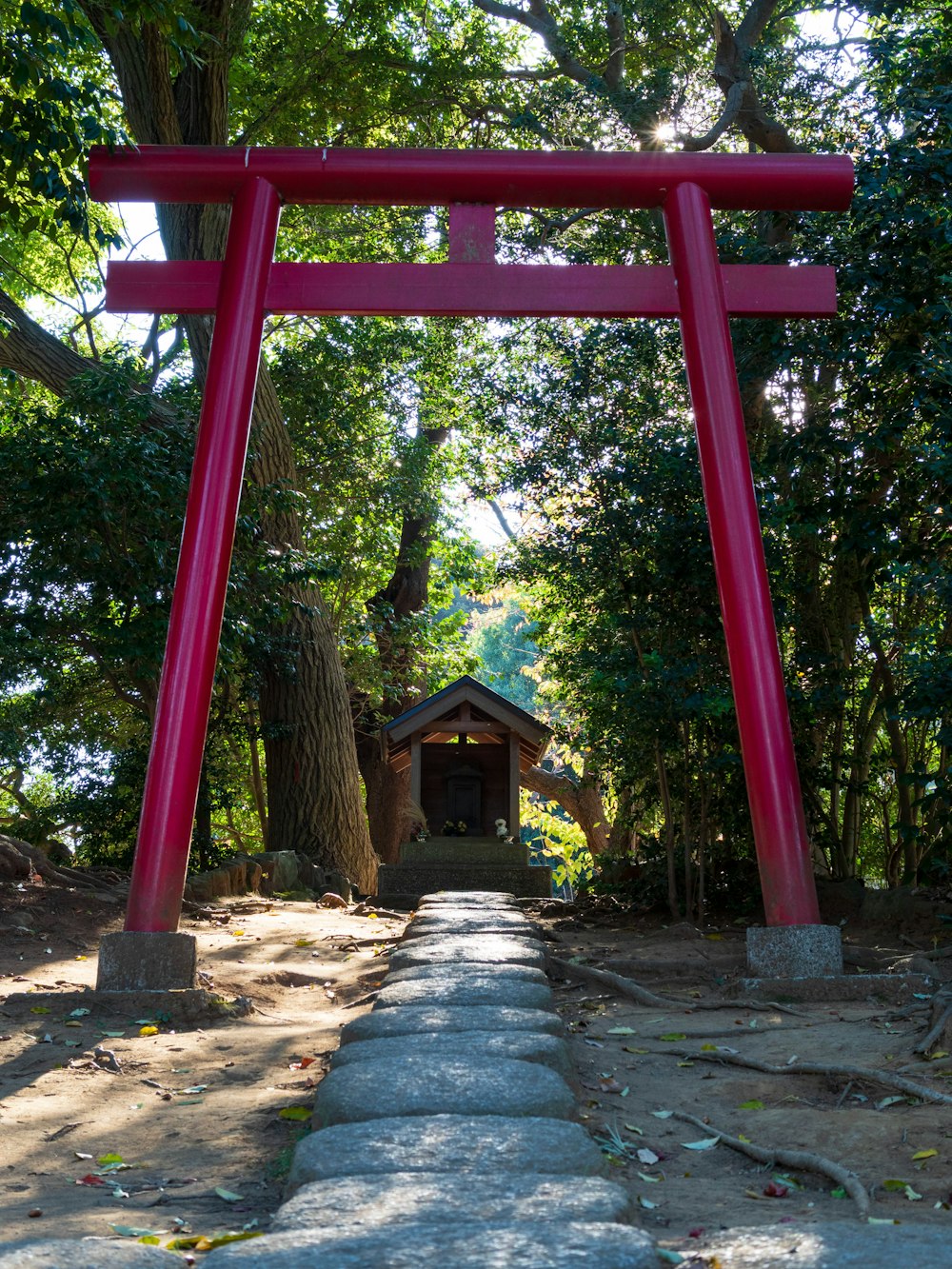 a red arch with a small building in the background