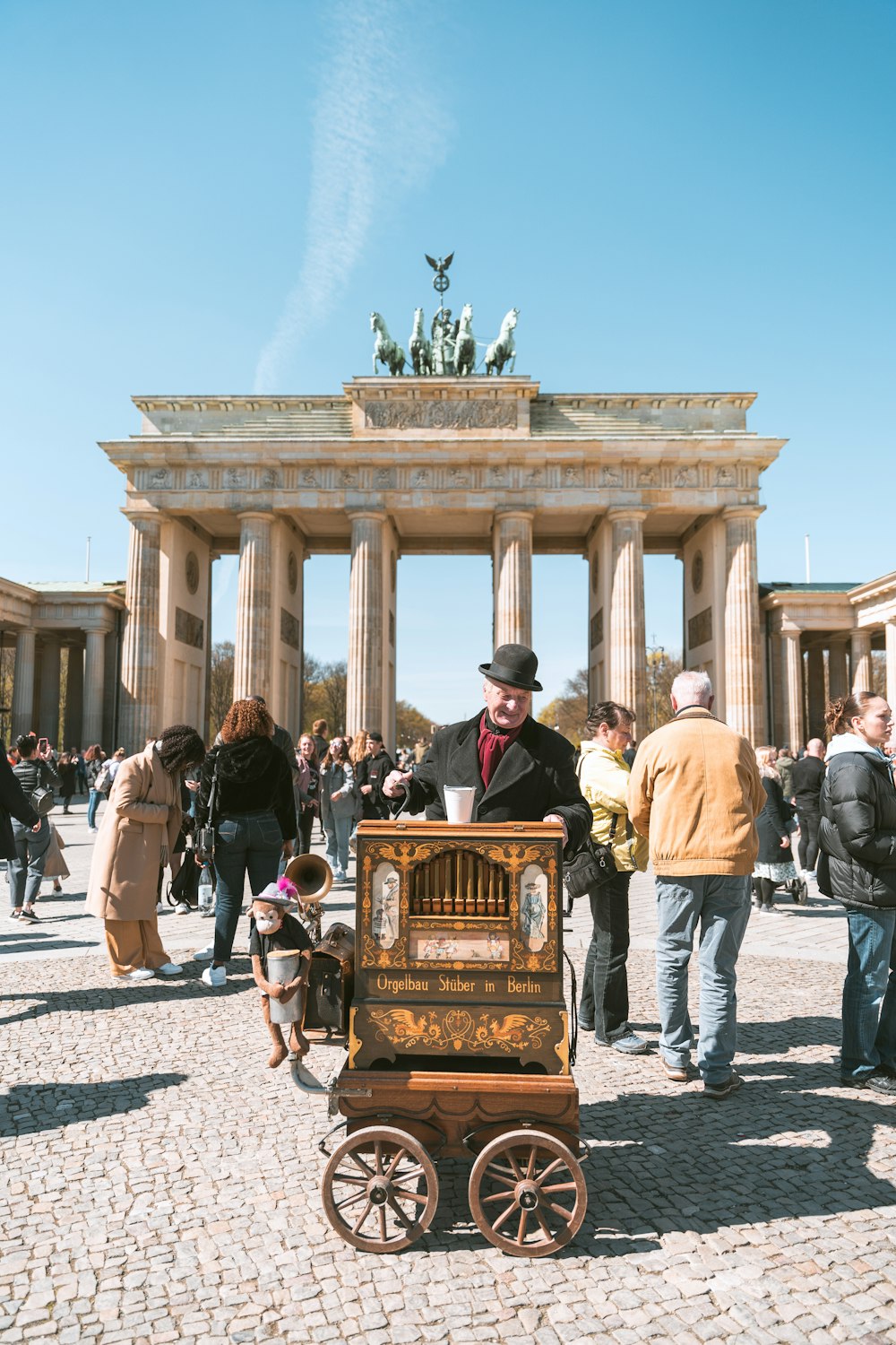 a person in a hat standing next to a cart with a statue on top of it