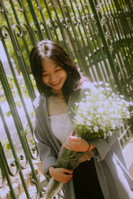 Katharine holding a bouquet of white and lavender flowers, her smile radiant in the gentle sunlight.