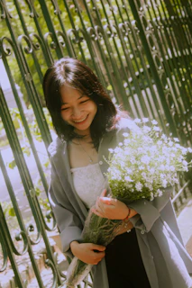 Katharine holding a bouquet of white and lavender flowers, her smile radiant in the gentle sunlight.