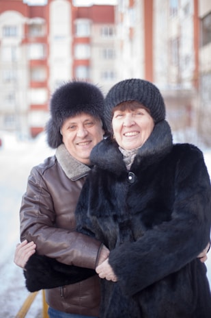 A happy couple wearing matching colorful scarves, smiling outdoors on a crisp winter day.