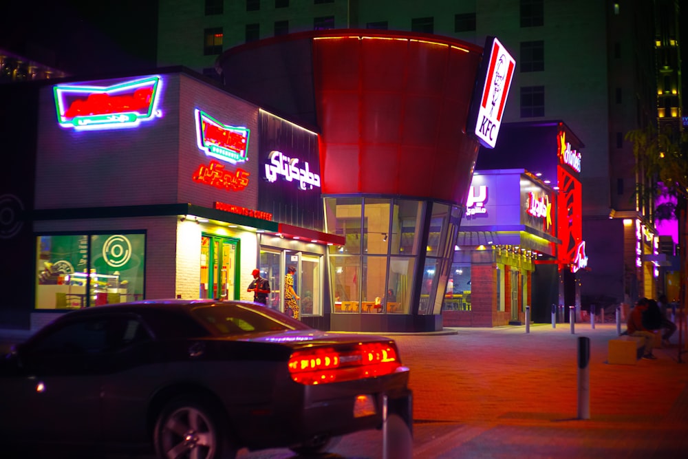 a car parked in front of a building with neon signs