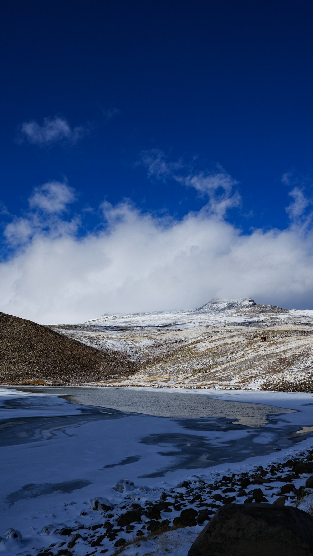 a snowy landscape with a body of water and a blue sky