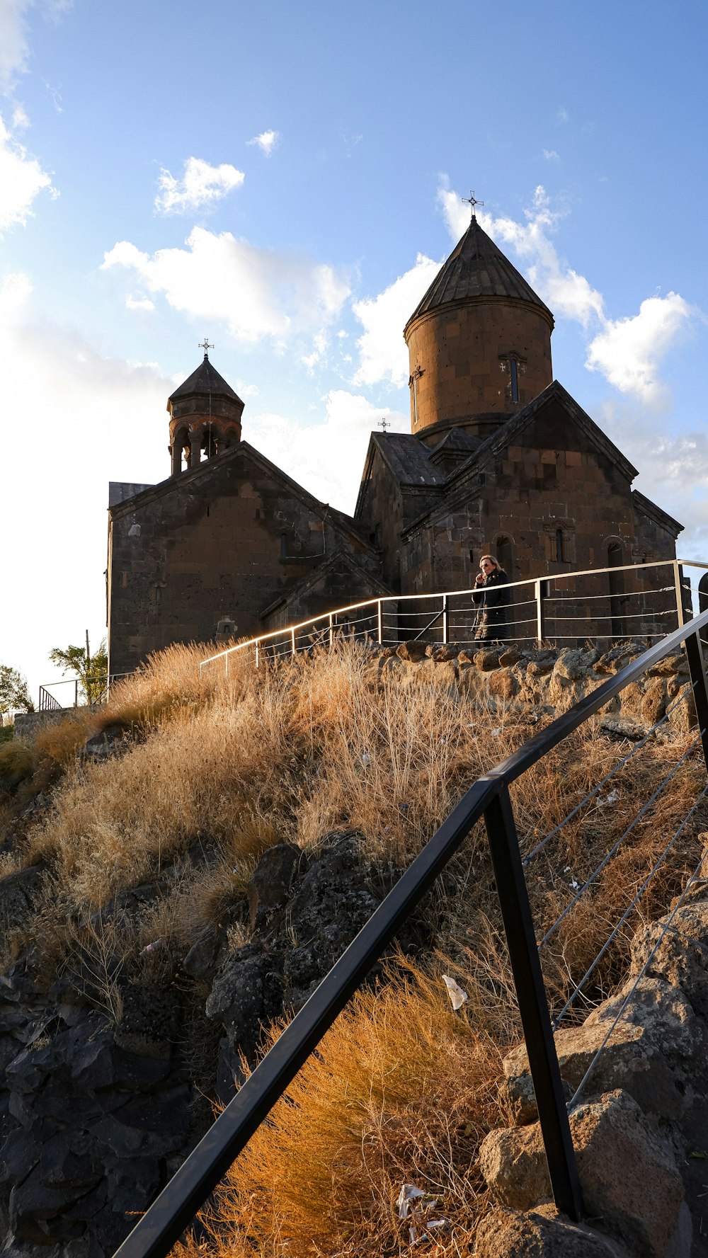 a castle with a fence and a person standing on a rock