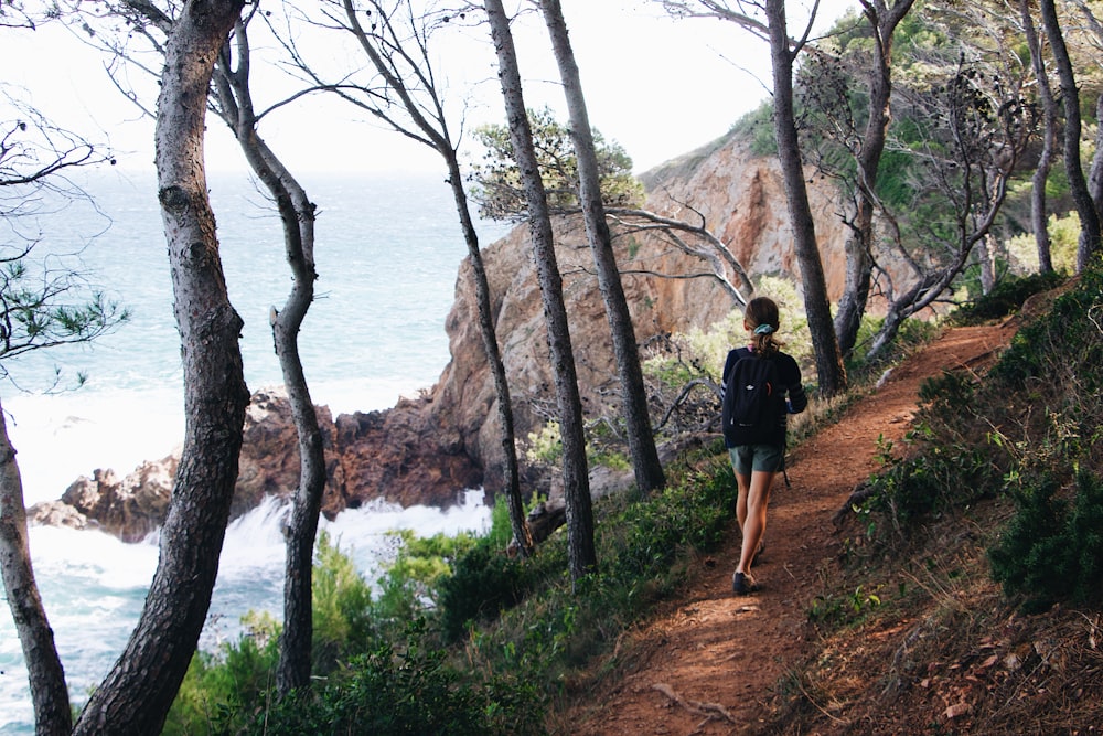 a man walking on a trail by a body of water