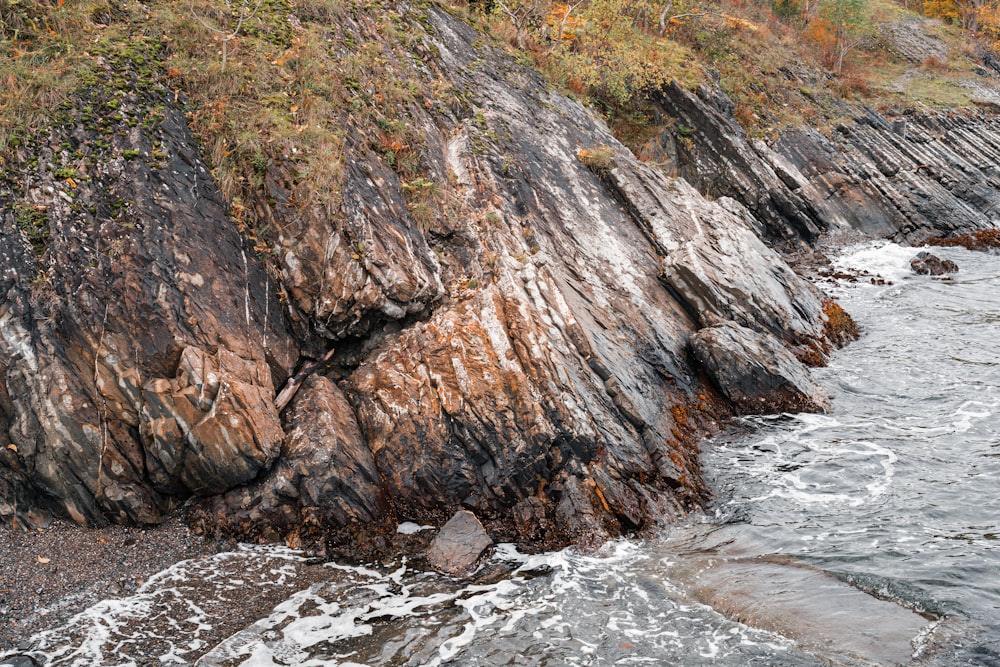 a rocky cliff next to a body of water