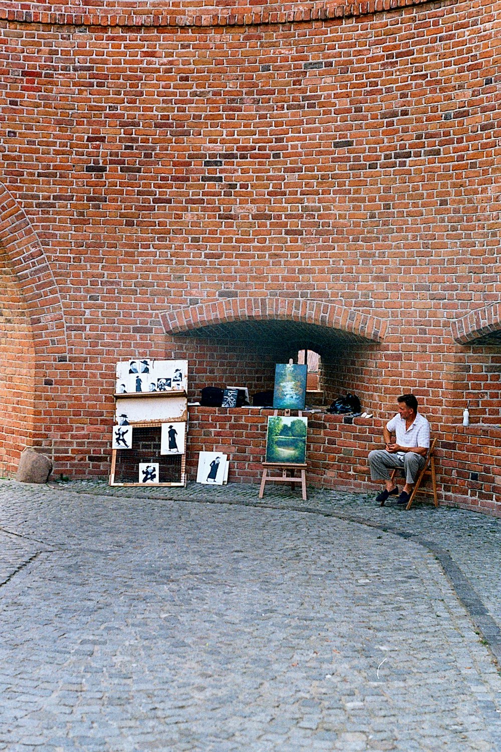 a person sitting on a bench in front of a brick building