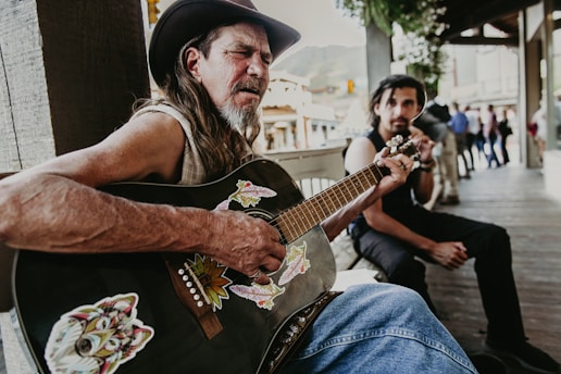 a man playing a guitar next to a woman sitting on a bench