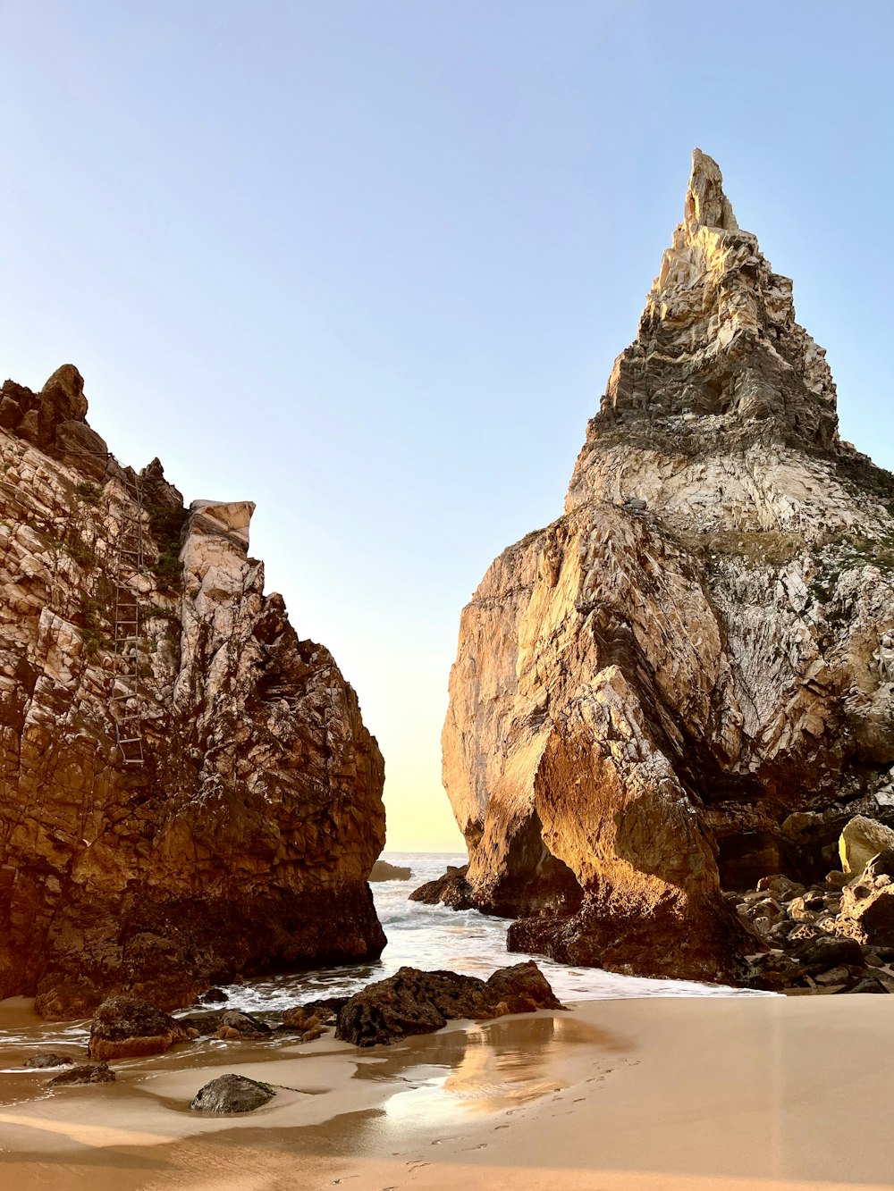 a rocky beach with a large rock formation in the background