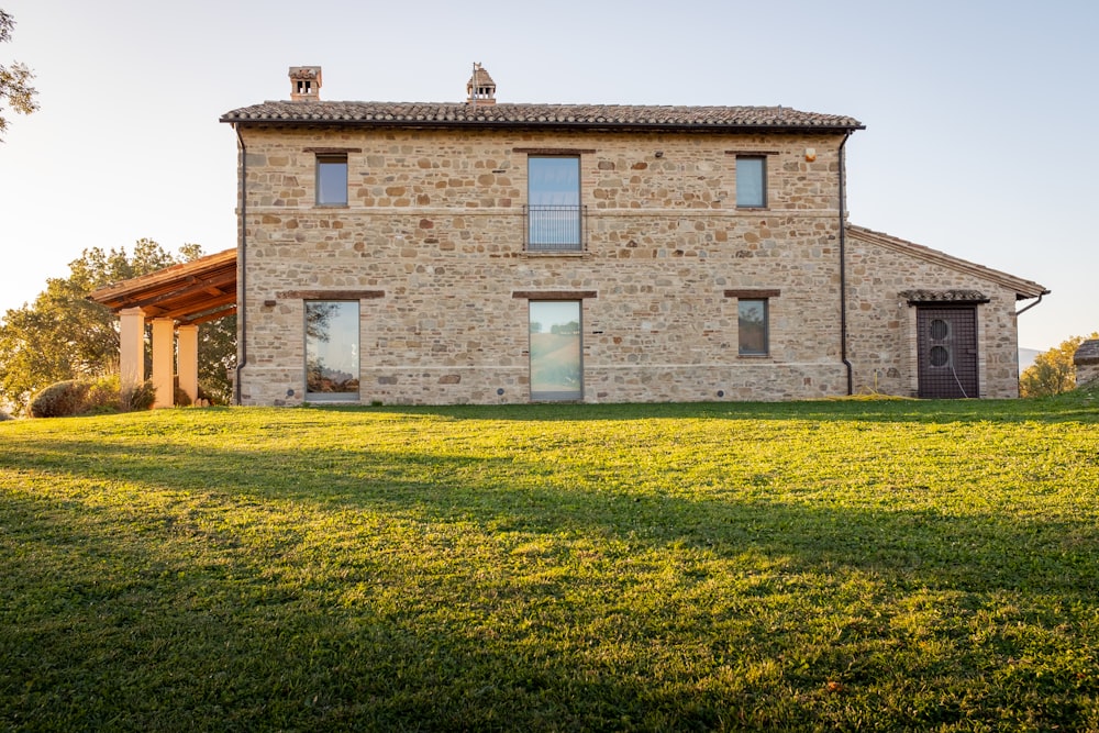 un bâtiment en pierre avec un champ d’herbe