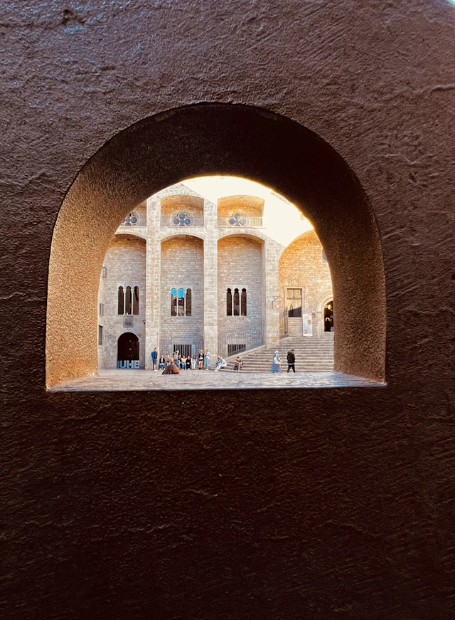 Looking through an archway onto the Gothic stone courtyard and staircase of Placa del Rei in the Gothic Quarter