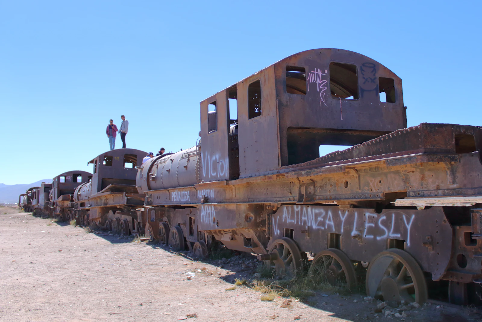 Tren abandonado con personas en el Cementerio de Trenes, Salar de Uyuni, Bolivia