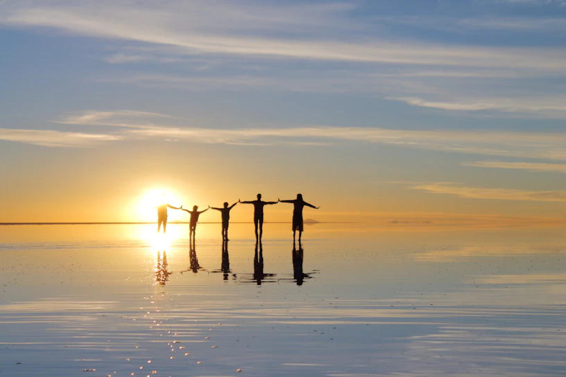 a group of people standing on a beach with a sunset in the background