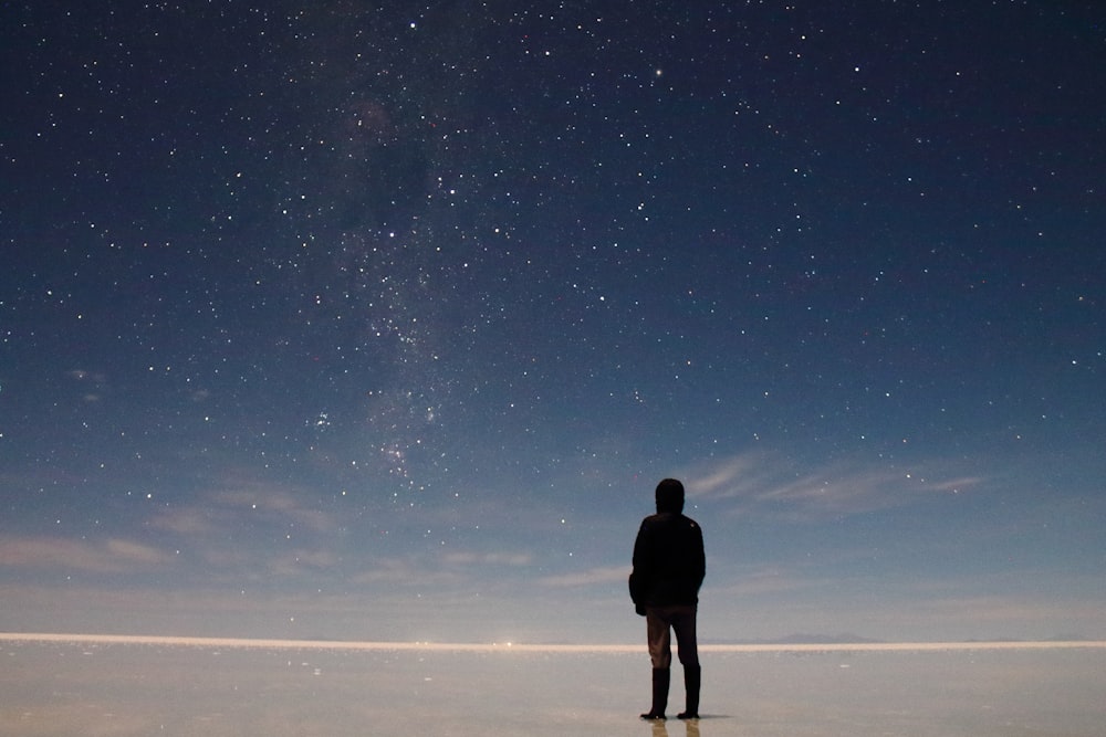 空に星が浮かぶ野原に立つ男