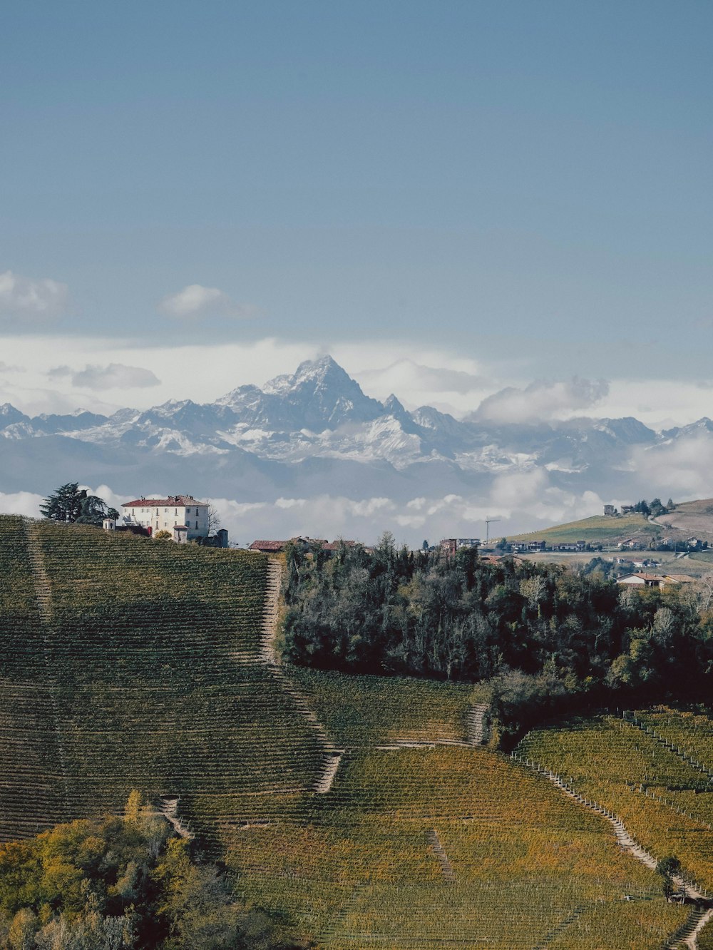 a large stone wall with a building and mountains in the background