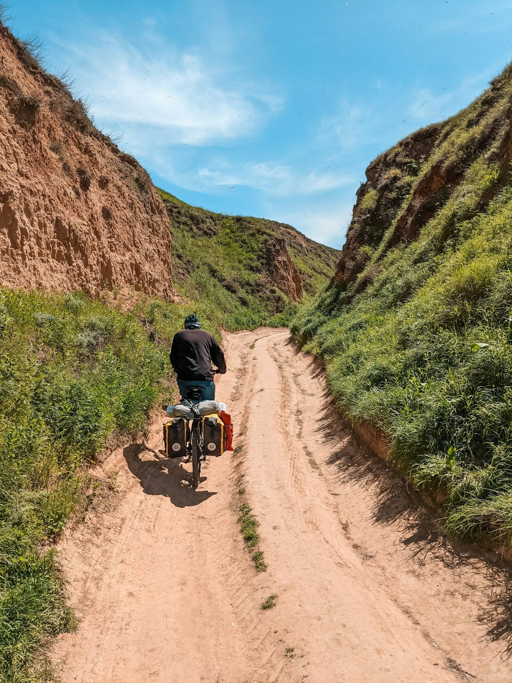 a man riding a motorcycle on a dirt road between mountains