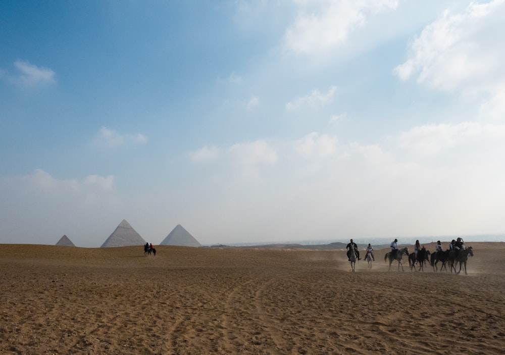 a group of people riding camels in front of pyramids