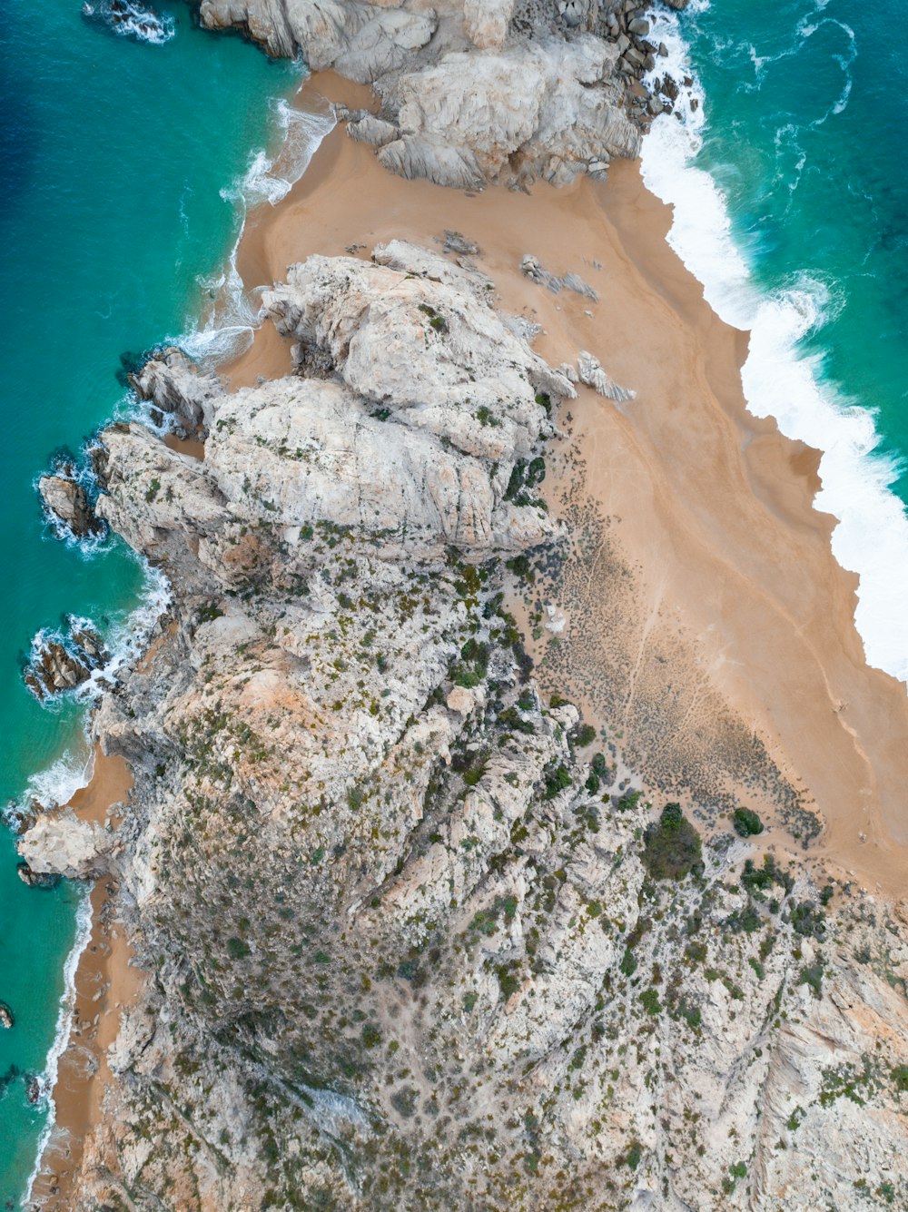 a rocky beach with a body of water in the background