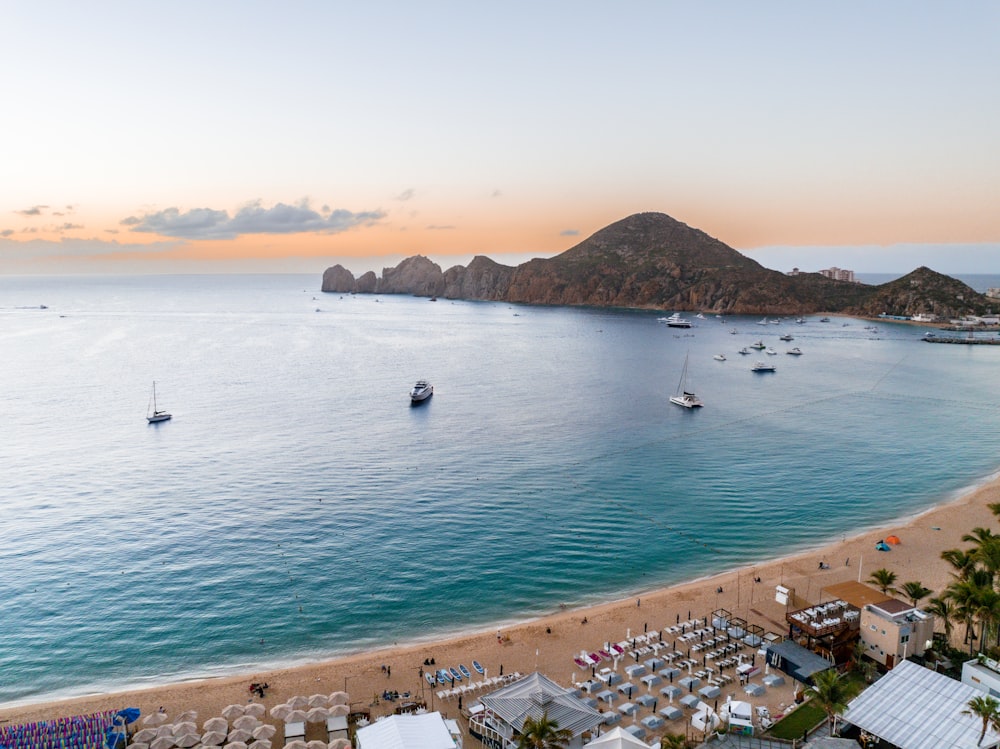 Una playa con barcos y una colina al fondo