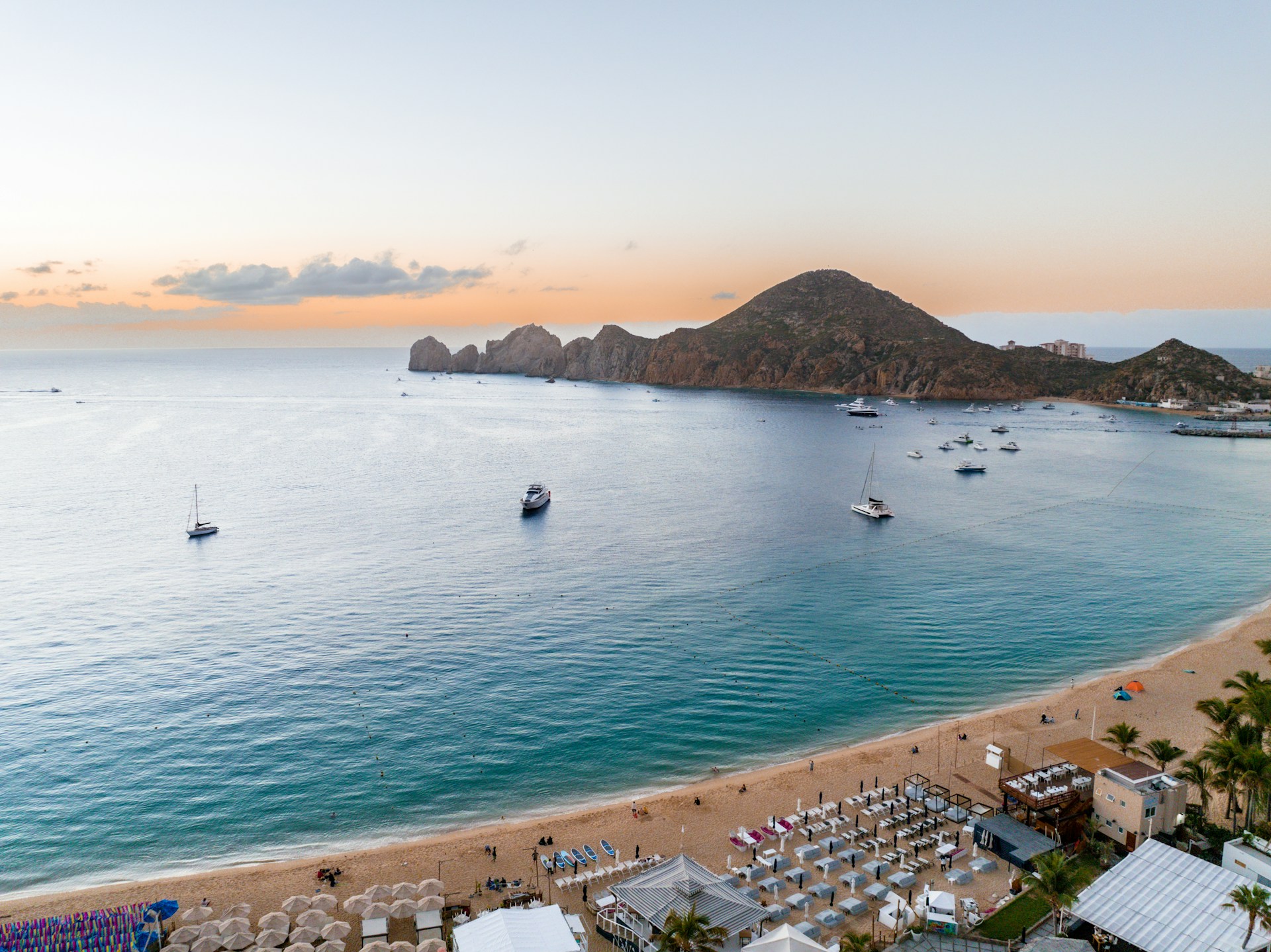 a beach with boats and a hill in the background