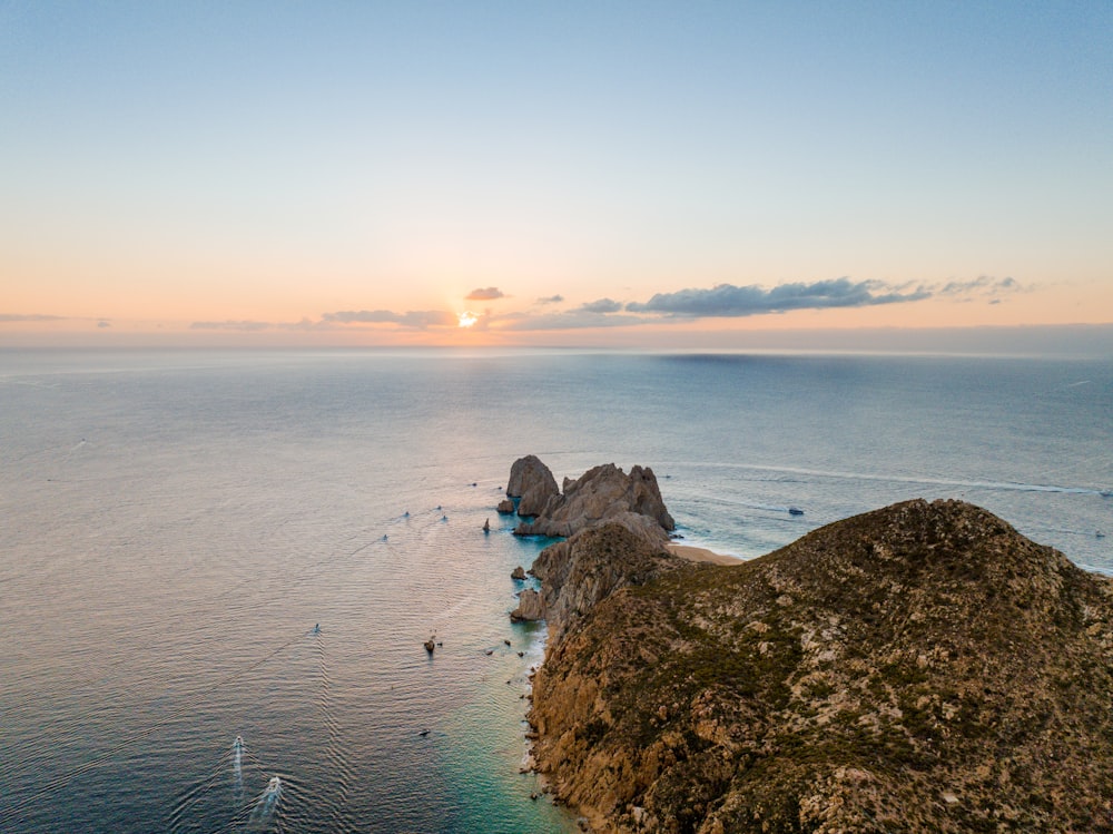 un cuerpo de agua con rocas y una puesta de sol