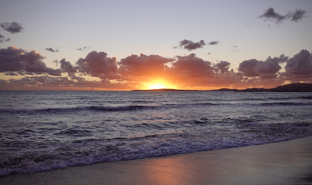 a beach with waves and a sunset