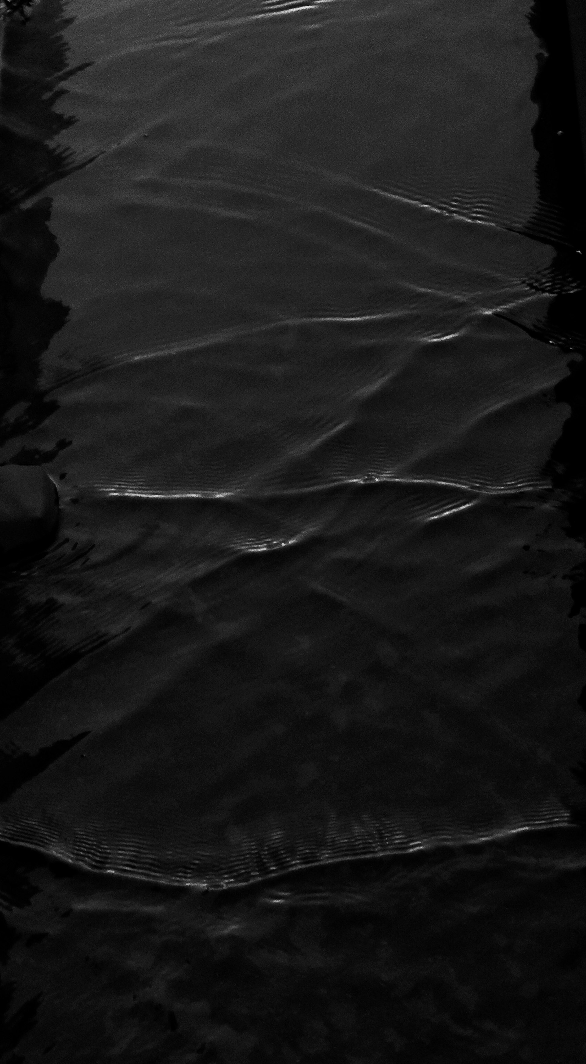 a black and white photo of a road with a puddle of water