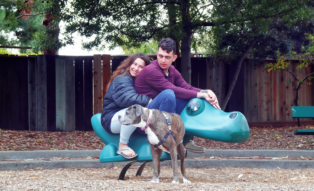 a man and woman sitting on a bench with a dog