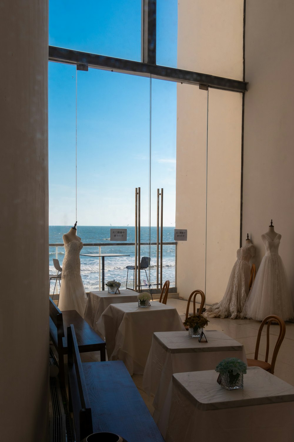 a room with tables and chairs and a view of the ocean